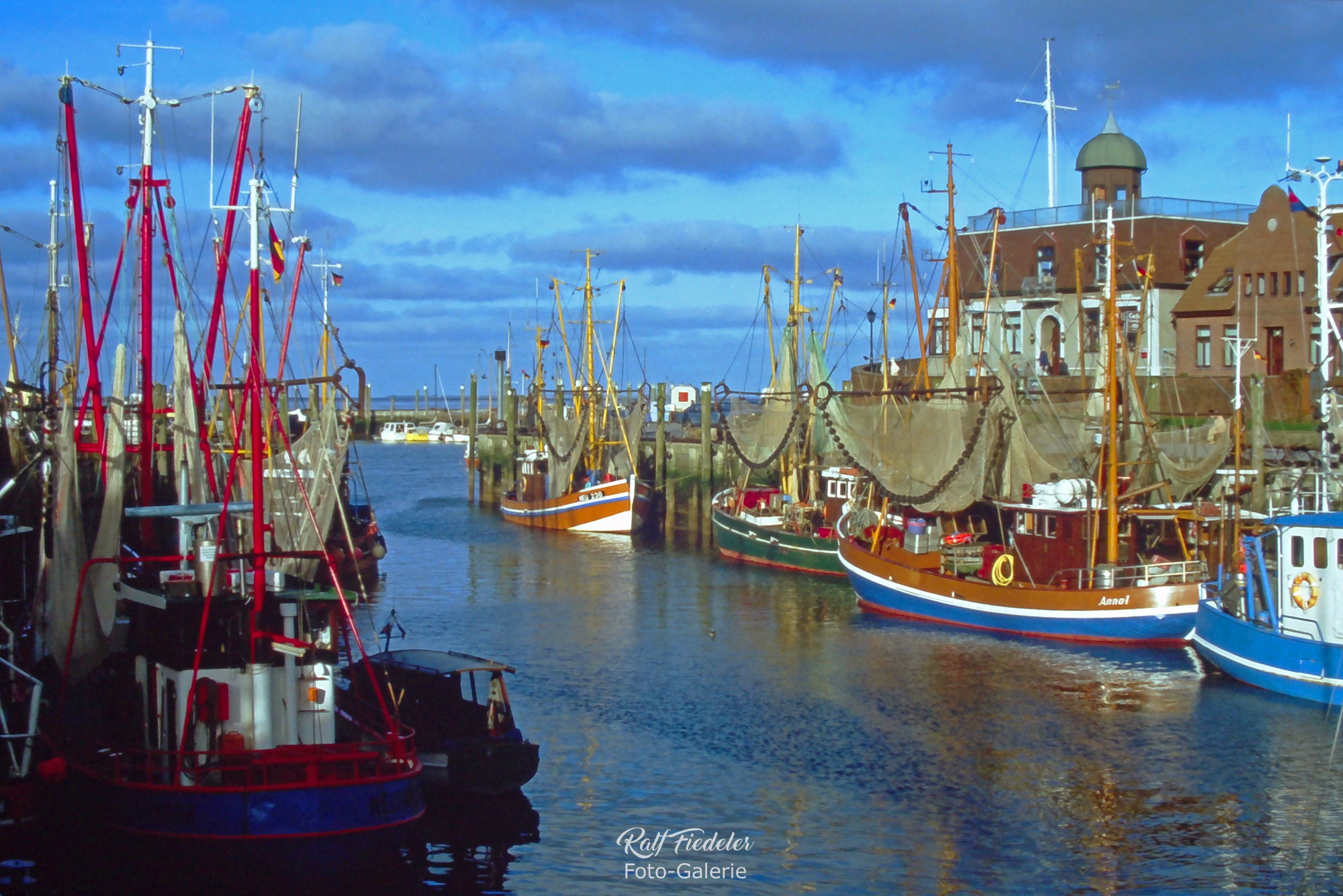 Fischkutter in Neuharlingersiel mit Café Störmhuus