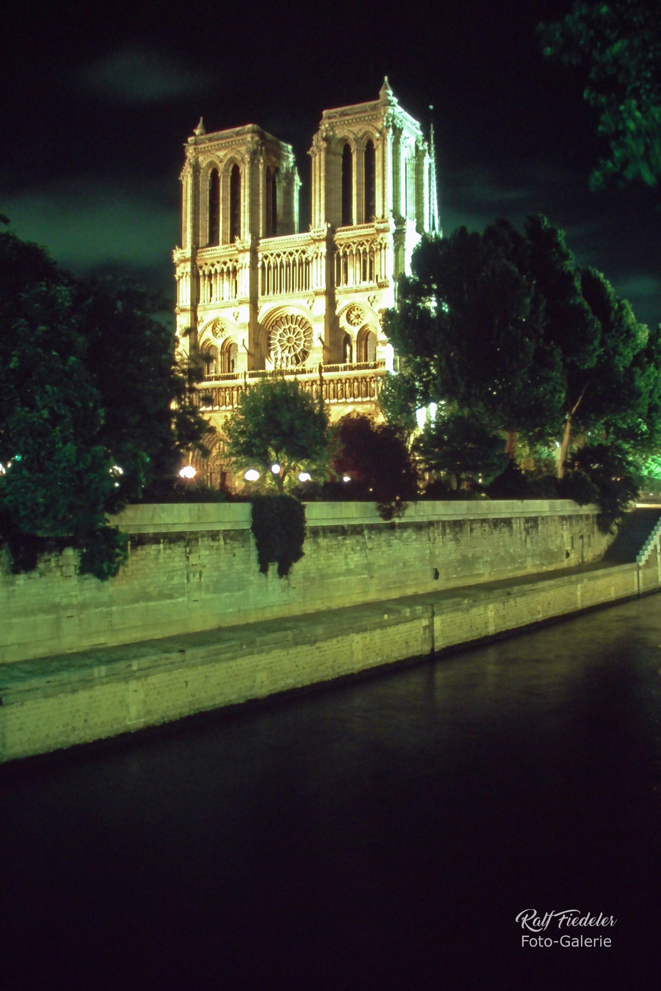 Beleuchtete Kathedrale Notre-Dame in Paris bei Nacht mit der Seine im Vordergrund