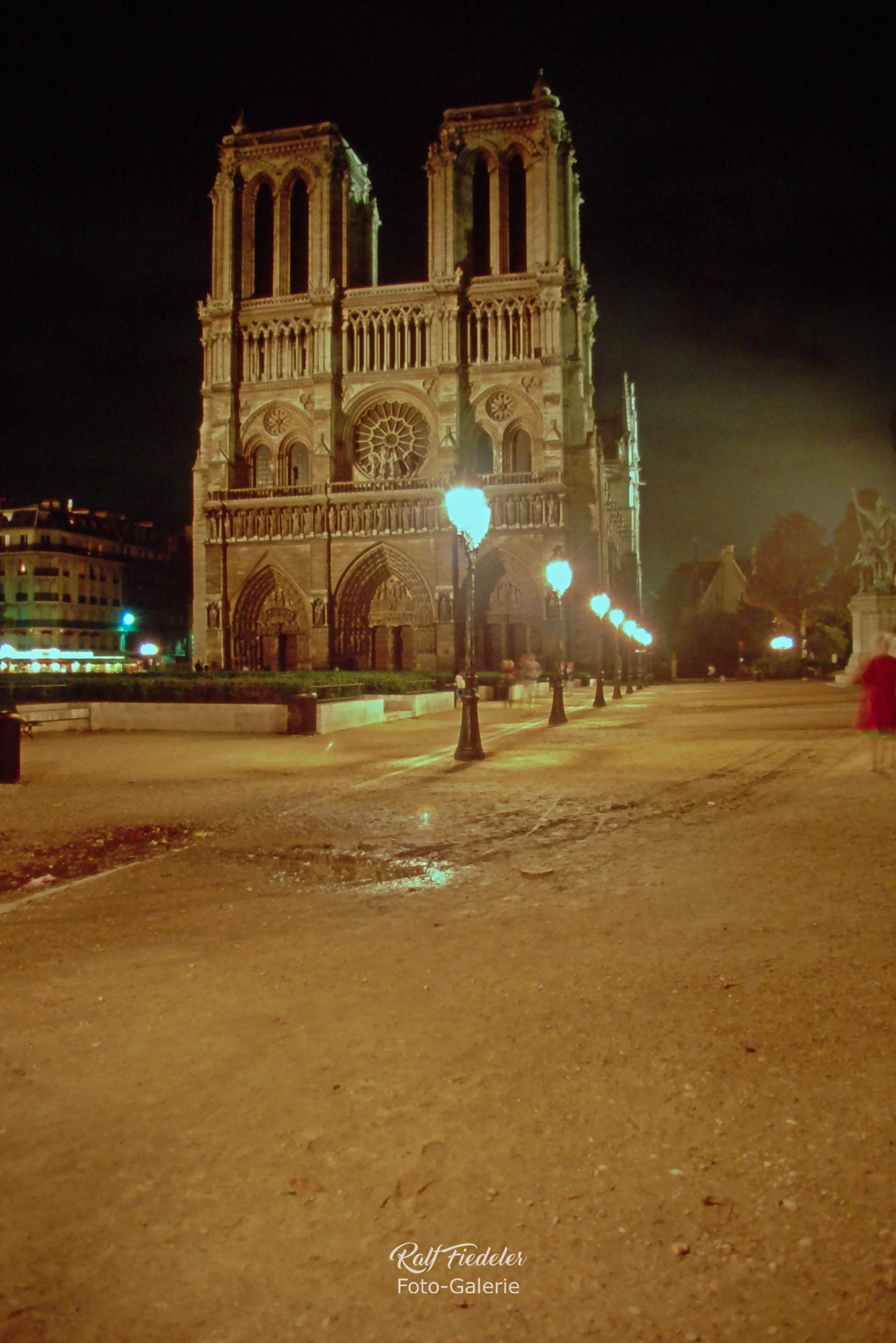 Beleuchtete Kathedrale Notre-Dame in Paris bei Nacht vom Nullpunkt französischer Straßen aus