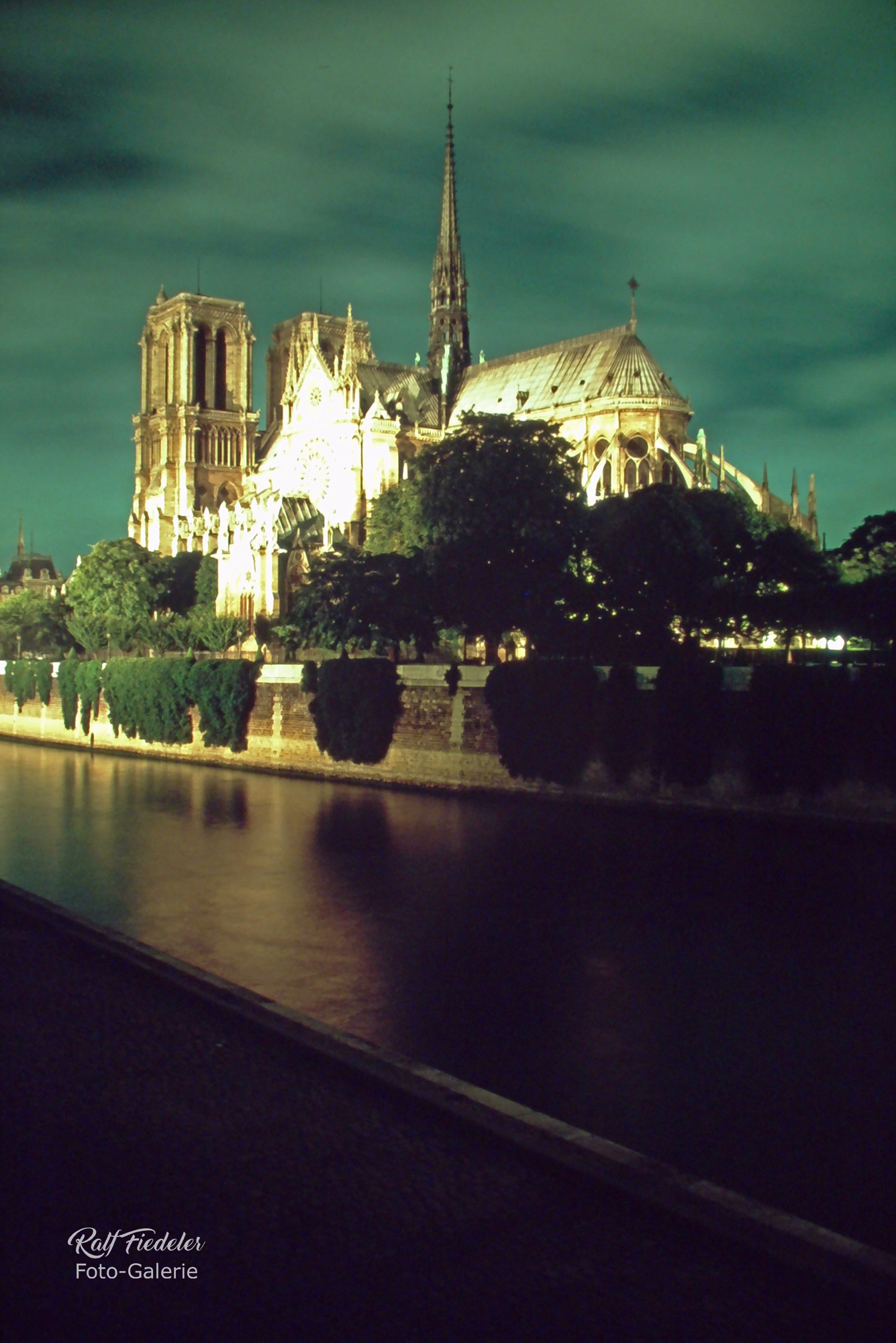 Beleuchtete Kathedrale Notre-Dame in Paris bei Nacht von schräg hinten