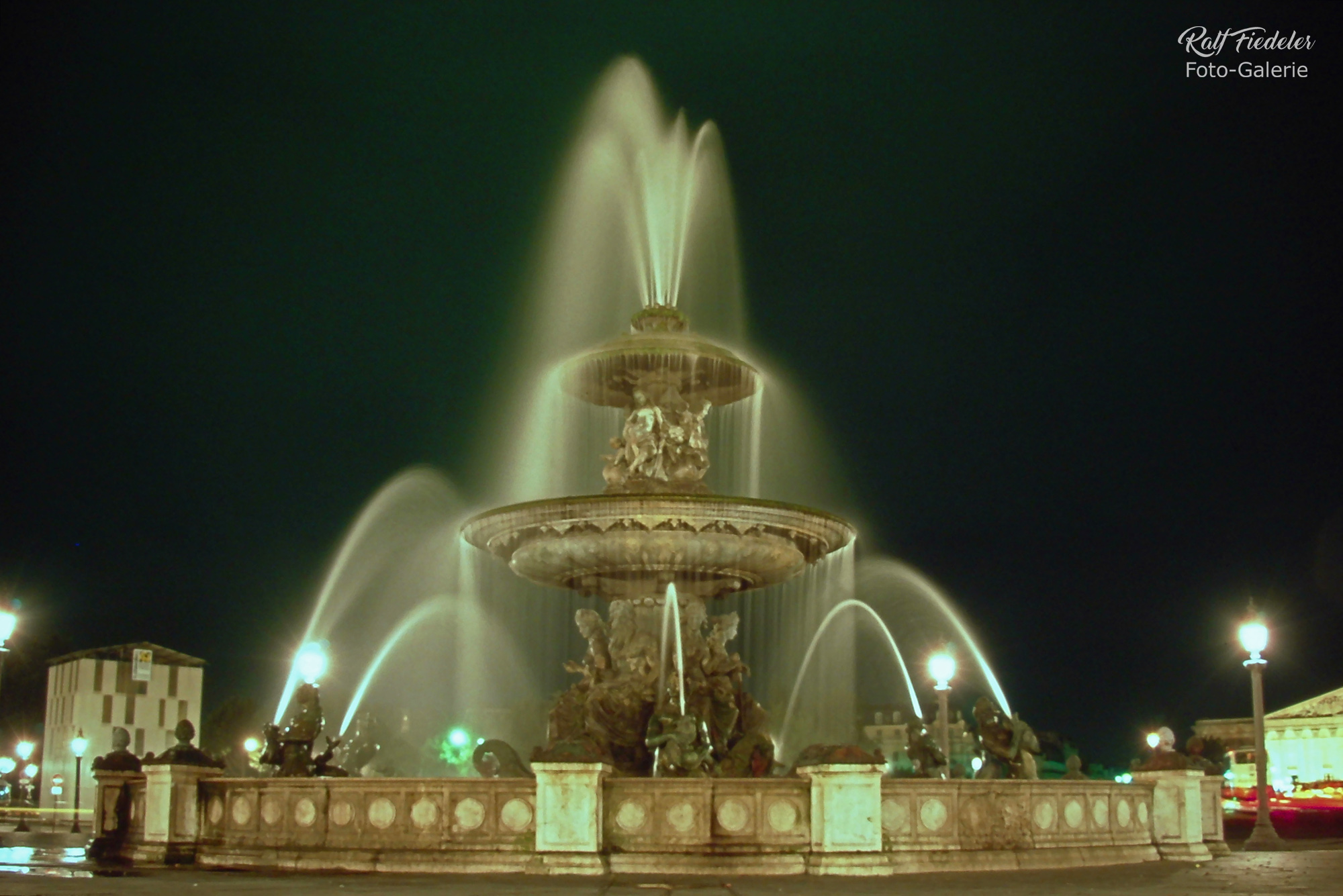 Langzeitaufnahme vom beleuchteten Flussbrunnen am Abend