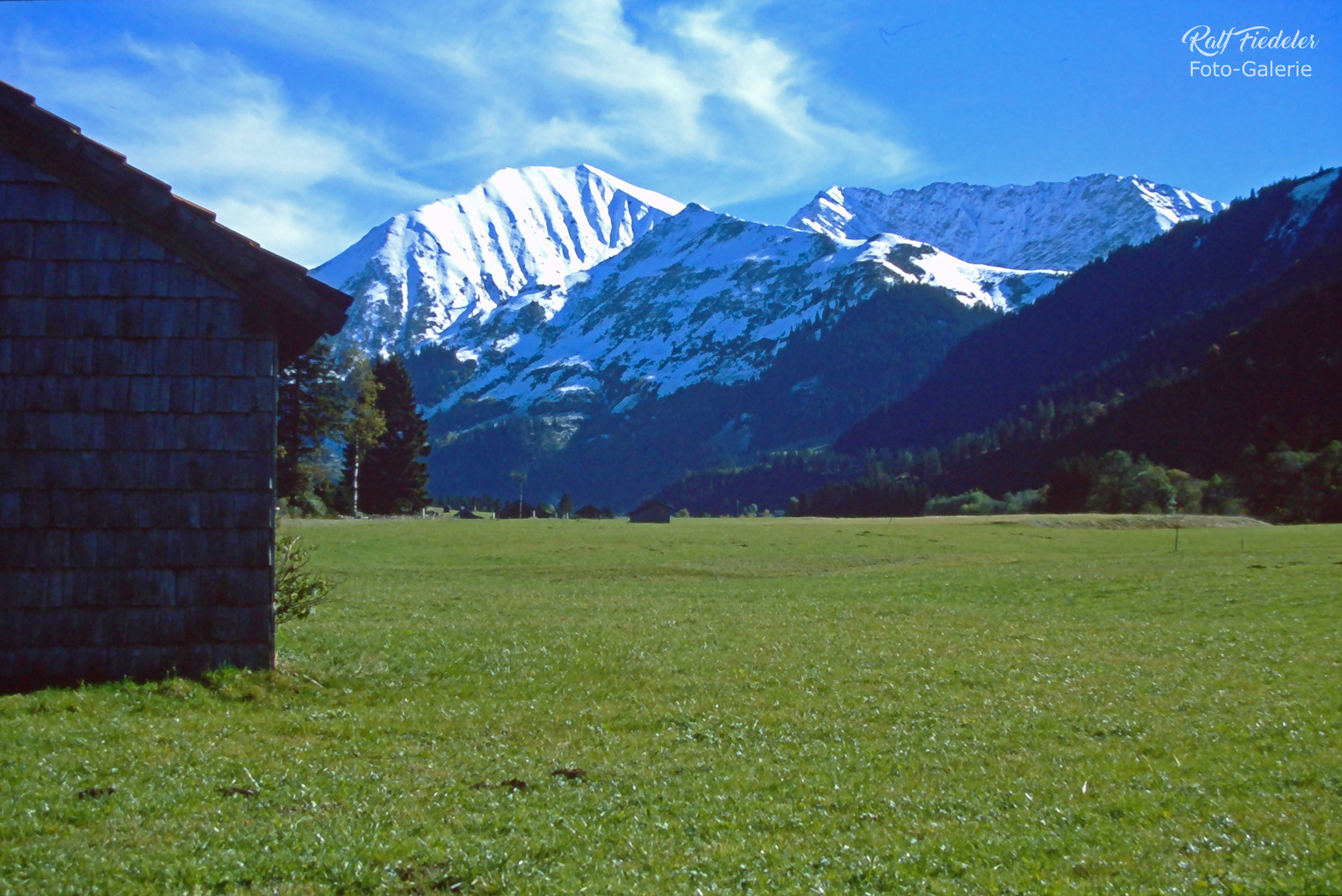 Holzhütte mit schneebedeckten Bergen im Hintergrund in Österreich