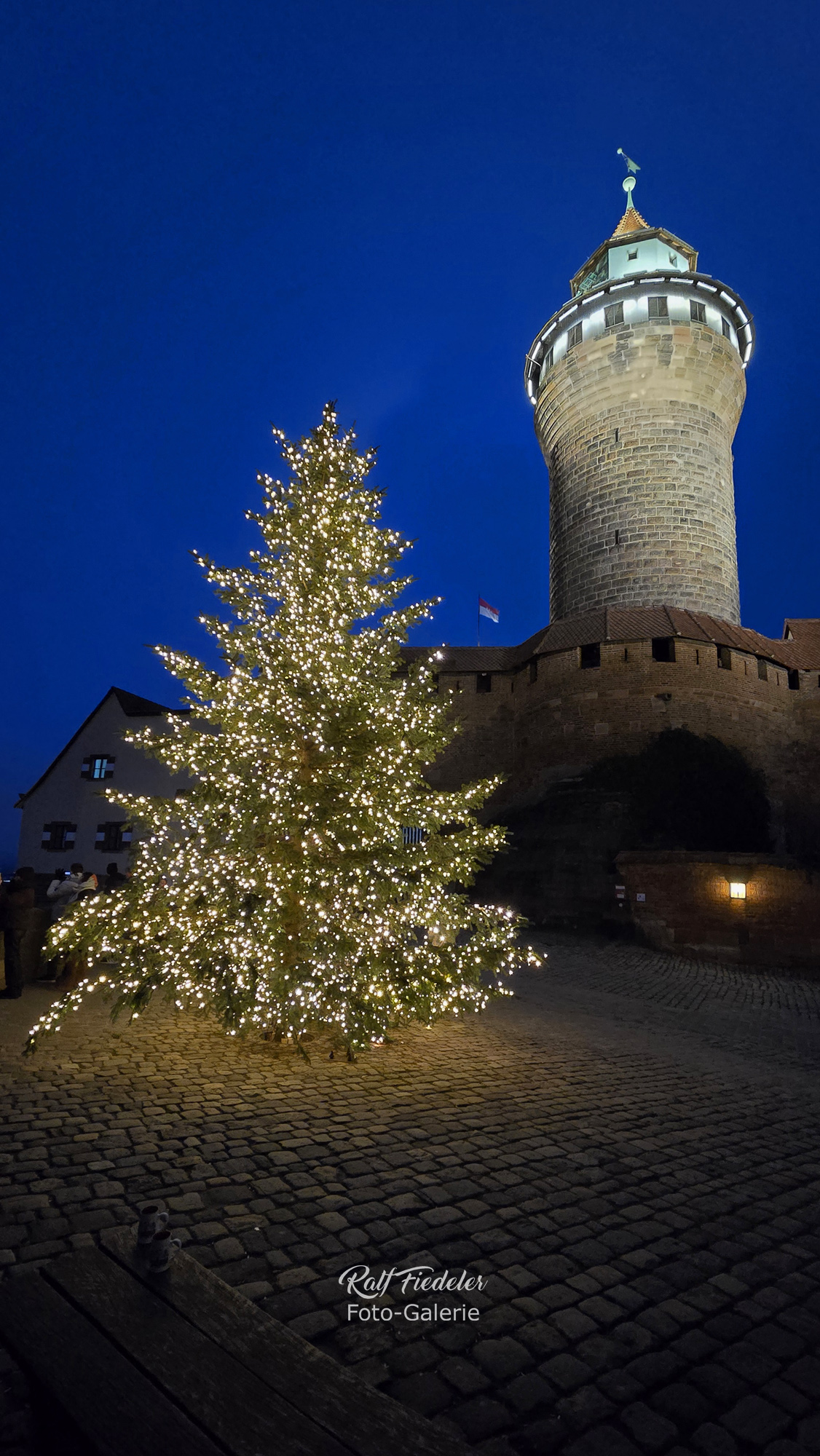 Beleuchteter Weihnachtsbaum und beleuchteter Sinwellturm der Kaiserburg in Nürnberg