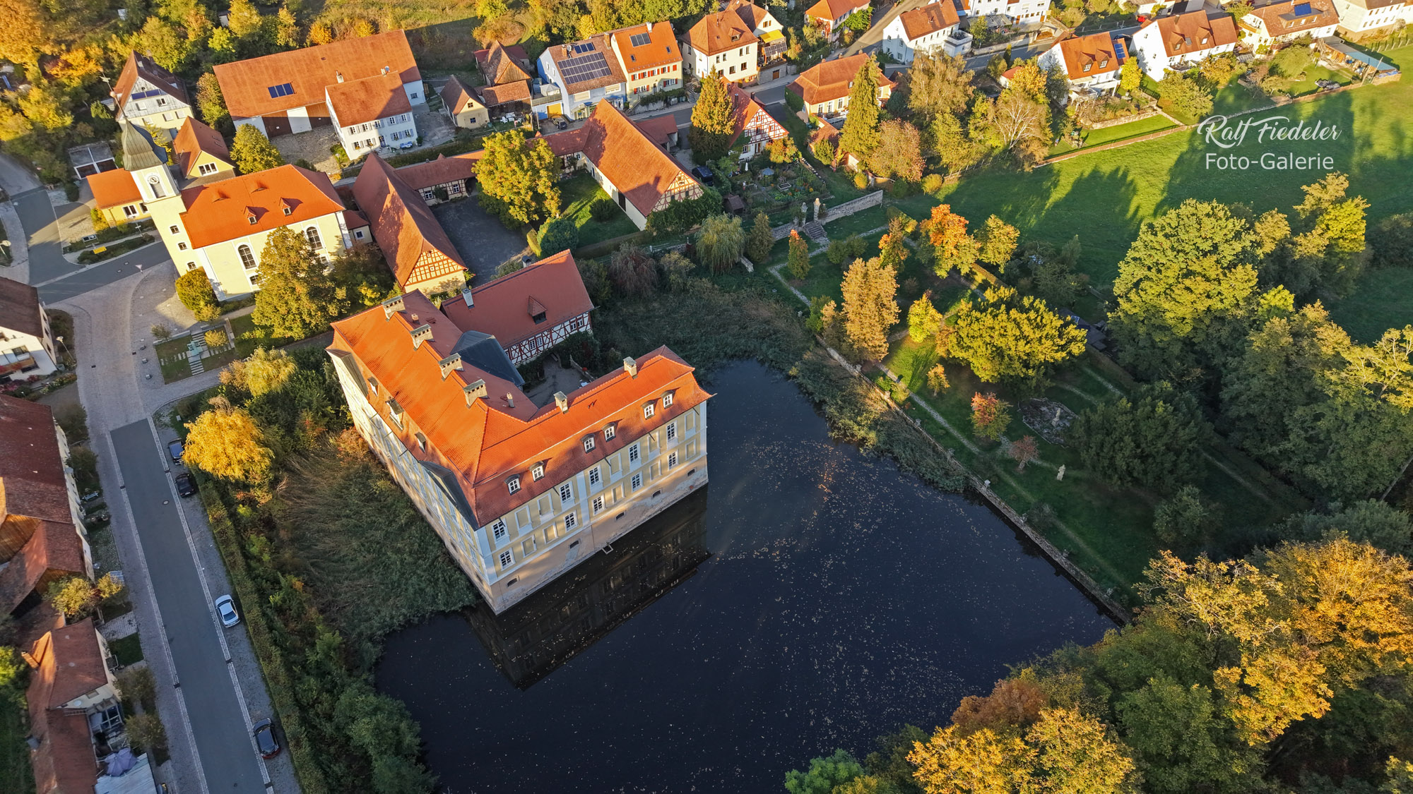Drohnenfoto vom Schloss Rügland südlich vom Wald aus etwas näher mit Park